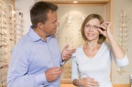 Couple trying on eyeglasses at optometrists smiling
